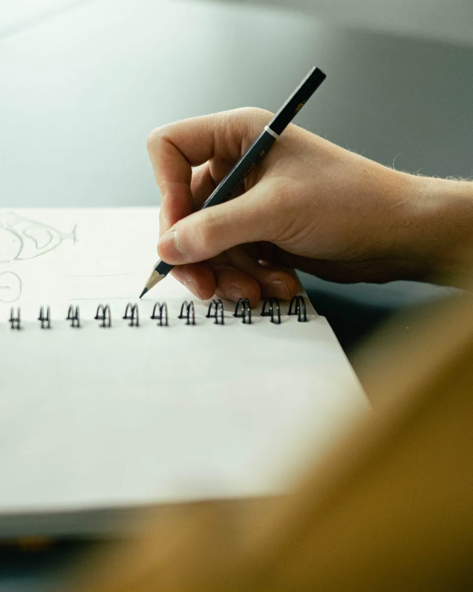 A hand sketching in a notebook