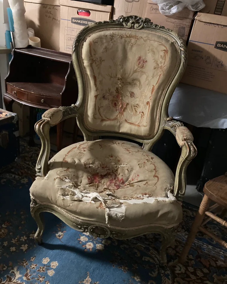 An antique armchair, torn, waiting in storage