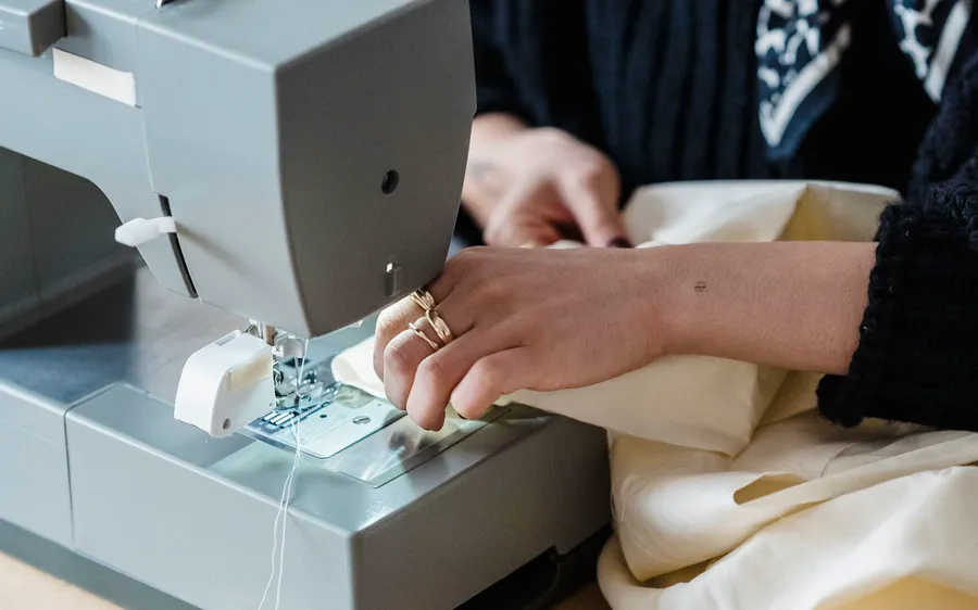 Hands guiding fabric through a sewing machine